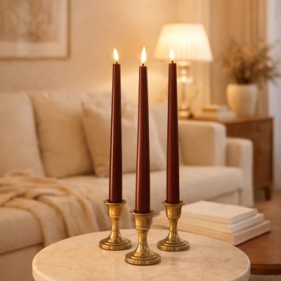 Três velas vermelhas finas em castiçais dourados numa mesa redonda de mármore