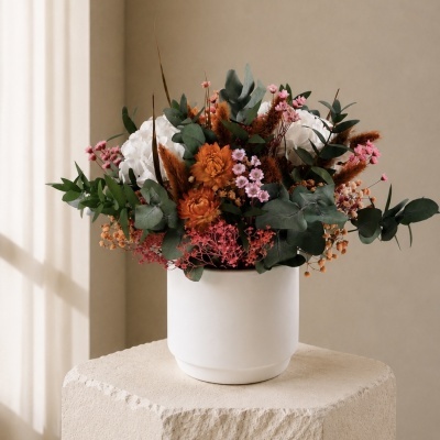 Arranjo floral colorido em vaso branco sobre pedestal bege