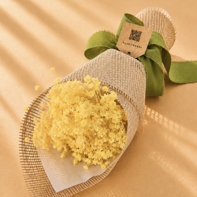 Buquê de flores secas amarelas com embalagem bege e fita verde