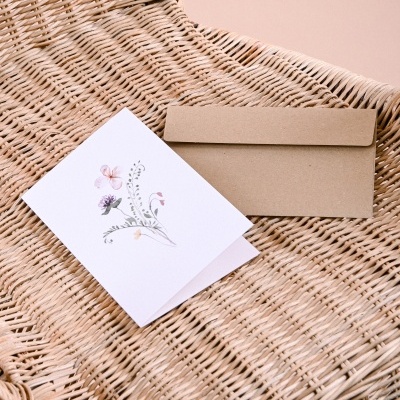 Cartão com flores e envelope sobre cadeira de vime