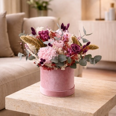Arranjo floral em vaso rosa sobre mesa de pedra em sala de estar