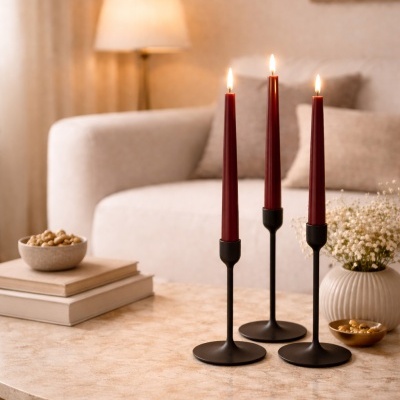 Três velas vermelhas em castiçais pretos sobre mesa de mármore clara