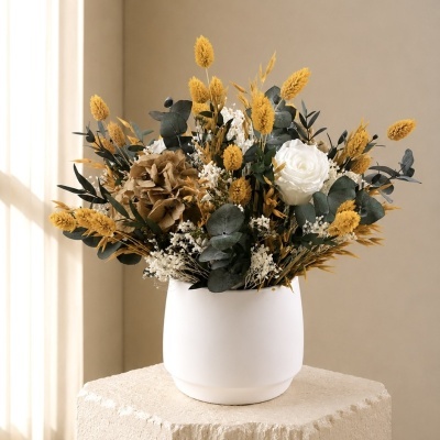 Arranjo de flores secas em vaso branco sobre pedestal bege