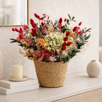 Arranjo de flores secas em cesto de palha sobre móvel de madeira clara