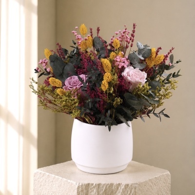 Arranjo floral colorido em vaso branco sobre pedestal creme