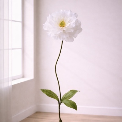 Flor artificial branca com base verde num chão de madeira junto a uma parede branca