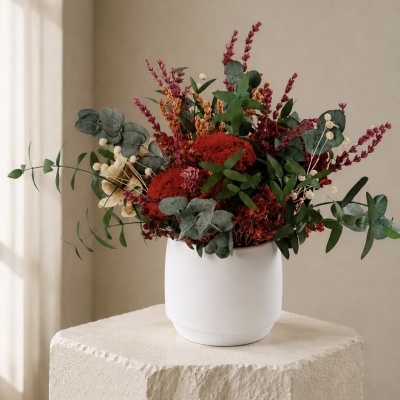Arranjo floral em vaso branco sobre bloco de pedra
