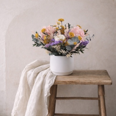 Arranjo floral colorido num vaso branco sobre banco de madeira