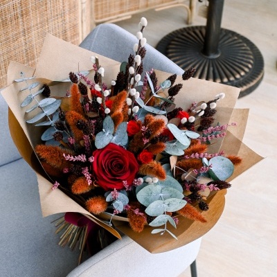 Buquê de flores secas e preservadas sobre cadeira cinzenta em sala clara