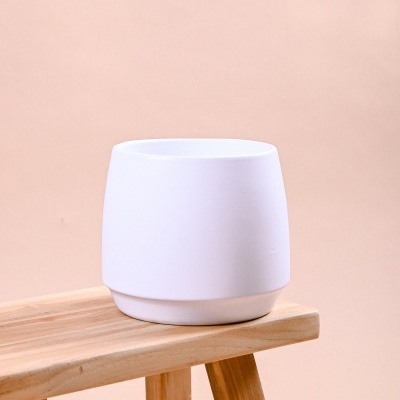 Vaso cerâmico branco sobre banco de madeira