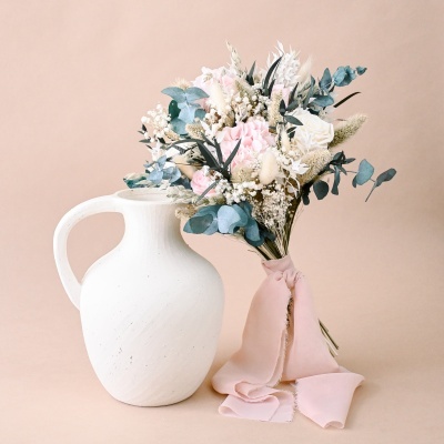Vaso branco de cerâmica com bouquet de flores secas e fita rosa claro