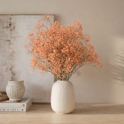 Vaso branco com flores cor de pêssego numa mesa de madeira com jarro e livros