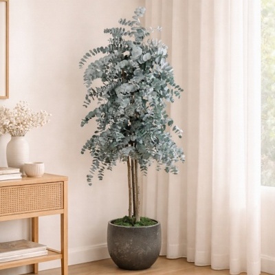 Árvore artificial com vaso preto num canto interior com cortinas brancas e mesa de madeira