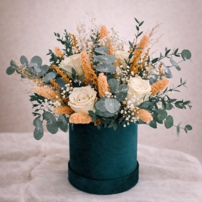 Arranjo floral com rosas brancas e flores secas num vaso verde-escuro