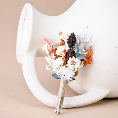 Pequeno ramo de flores secas coloridas apoiado em ânfora branca