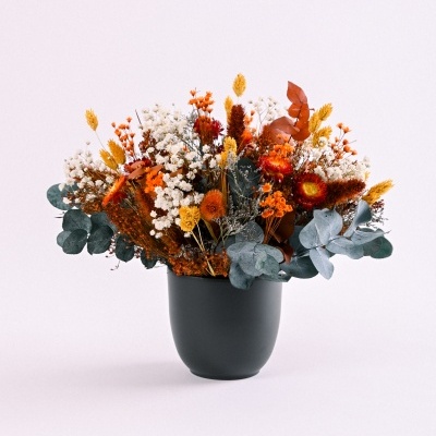 Arranjo floral seco em vaso preto com flores coloridas sobre fundo branco