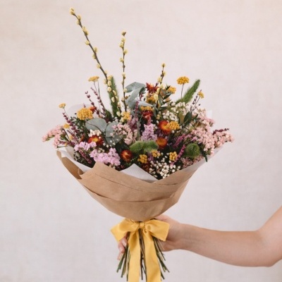 Buquê de flores coloridas com papel castanho e fita amarela