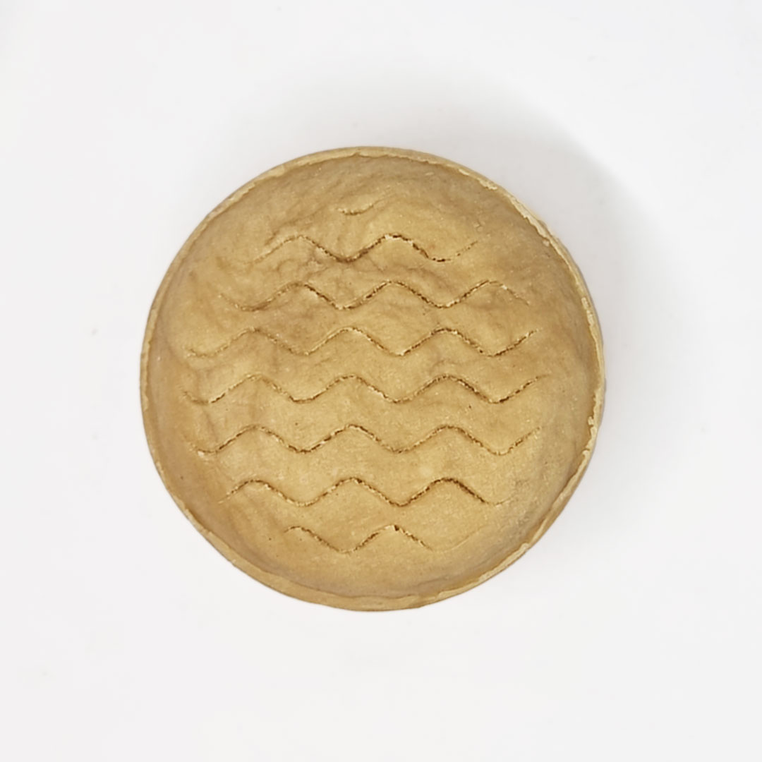 Champô Sólido Cabelo Ondulado - Bambu e Coco Prato redondo bege com padrão ondulado em relevo