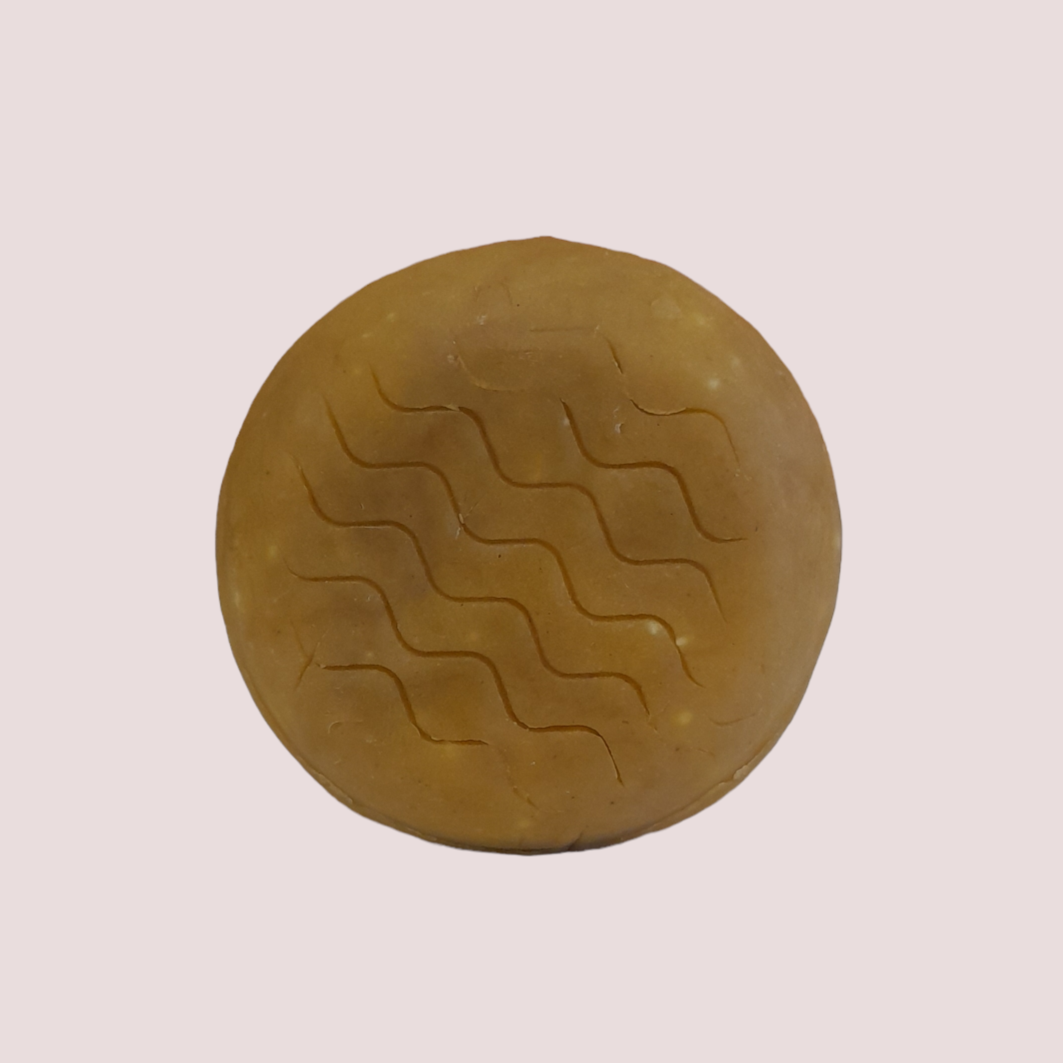 Champô Sólido Couro Cabeludo Sensível - Flor de Laranjeira e Alecrim Sabonete redondo bege com linhas onduladas gravadas