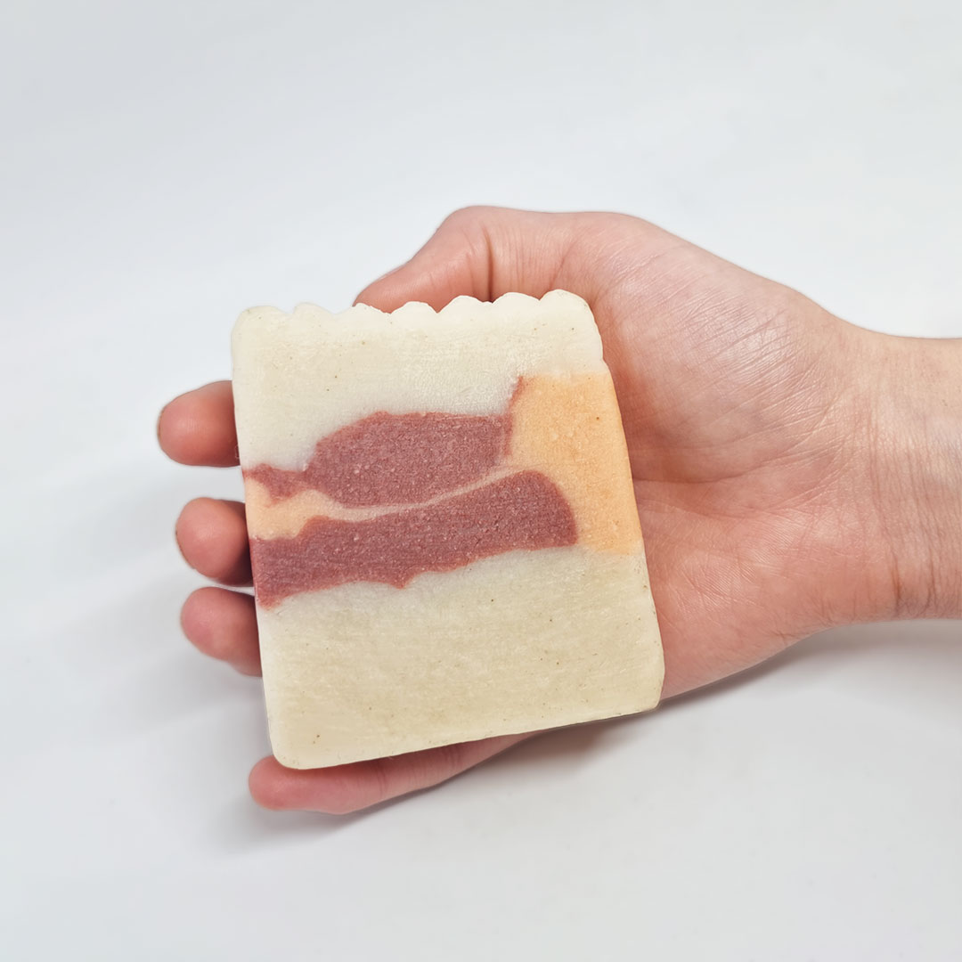 Sabonete de Madeira de Sândalo Sabonete artesanal quadrado com cores branco, rosa e bege numa mão