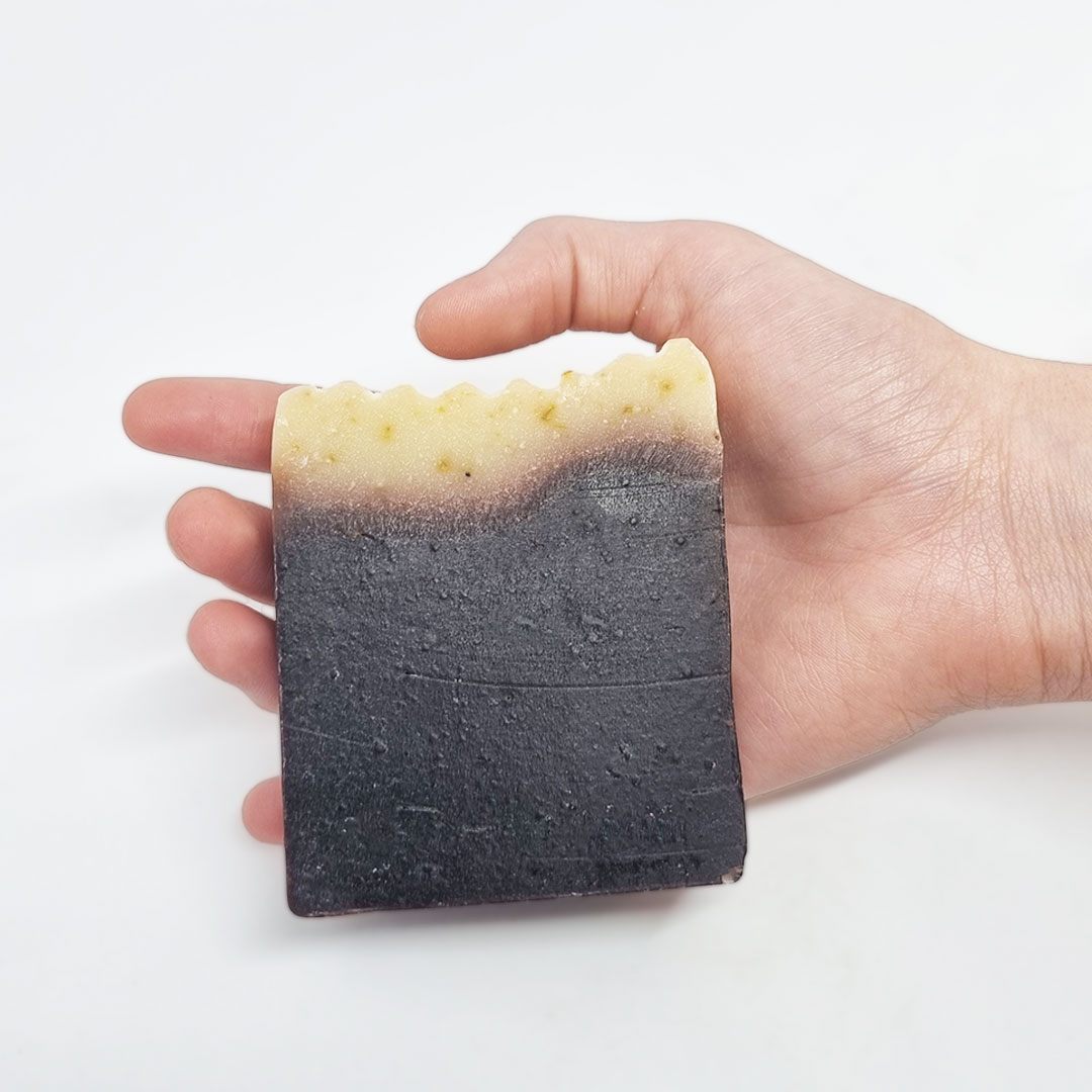 Sabonete de Aloé e Vera e Baunilha Sabonete retangular com camadas preta e amarela na mão