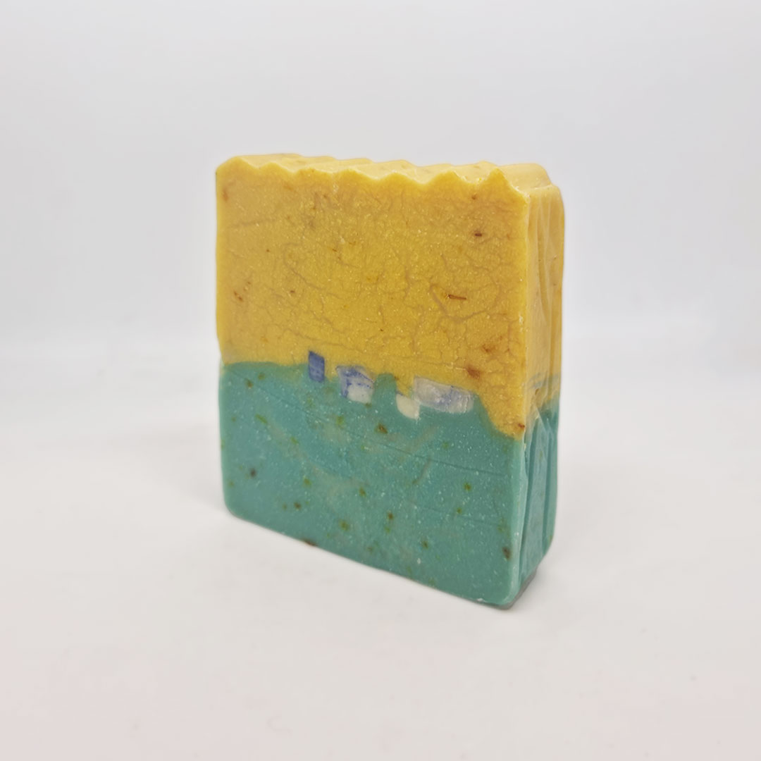 Sabonete de Cardamomo e Mimosa Sabonete artesanal amarelo e verde com textura ondulada no topo