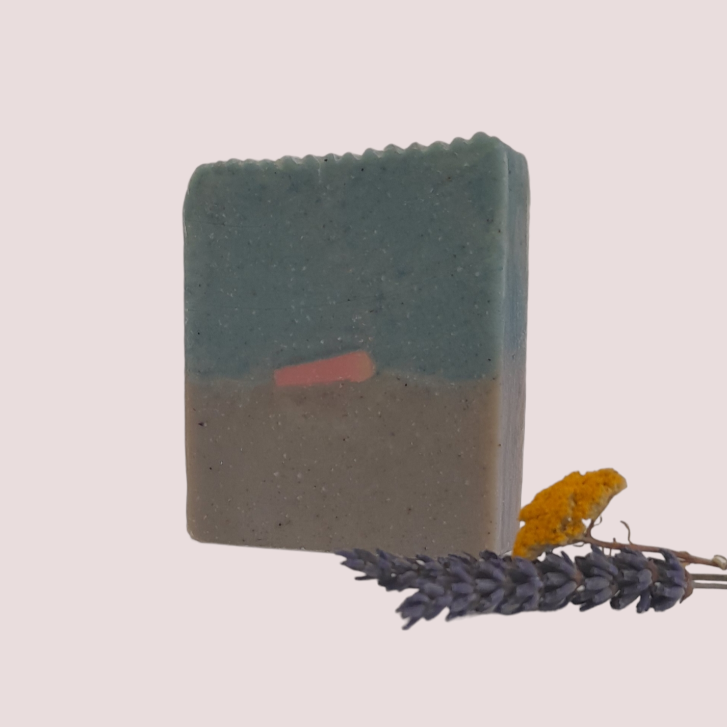 Sabonete de Folha de Chá, Jasmim e Fresia Sabão artesanal bicolor em fundo claro com flores secas ao lado