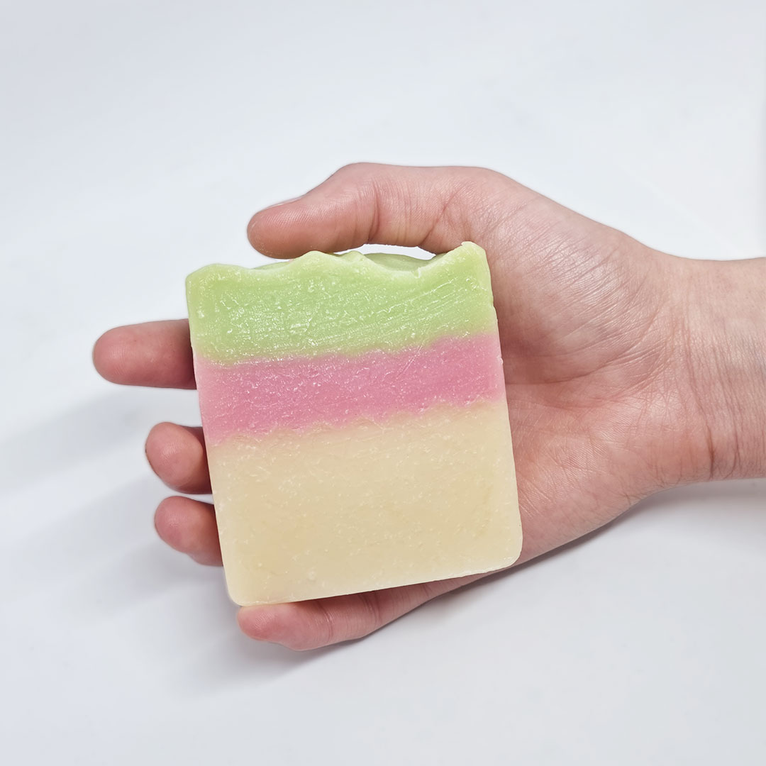 Sabonete Tutti Frutti Sabonete artesanal em barra com camadas verde, rosa e bege numa mão