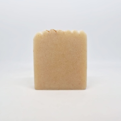 Sabonete quadrado bege claro com topo irregular num fundo branco