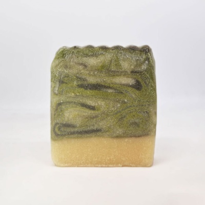 Sabonete artesanal verde e bege com textura ondulada no topo sobre fundo branco