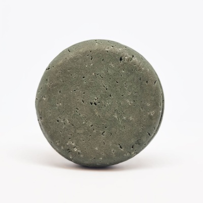 Sabonete redondo verde-acinzentado com textura rugosa