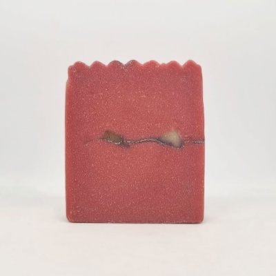 Sabonete artesanal vermelho com faixa central escura e borda ondulada