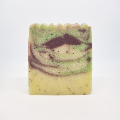 Barra de sabonete artesanal com cores amarelo, verde e roxo e partículas pretas