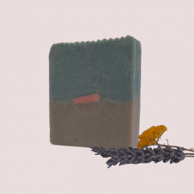 Sabão artesanal bicolor em fundo claro com flores secas ao lado