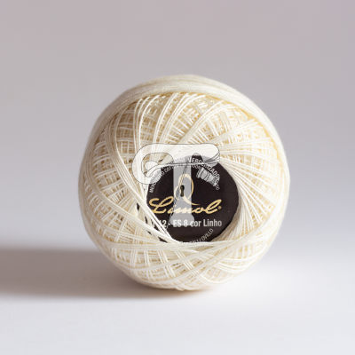 Novelo de linha cru com etiqueta preta no centro em fundo branco