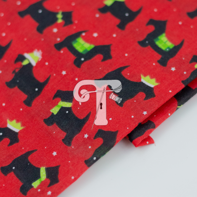 Tecido vermelho com padrões de cães pretos com cachecóis e gorros verdes