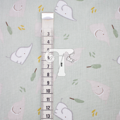 Fita métrica sobre tecido verde claro com padrão de elefantes e folhas.