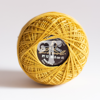 Novelo de linha de algodão amarelo com etiqueta preta no centro sobre fundo branco