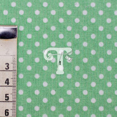 tecido verde com bolinhas brancas com régua de medida ao lado