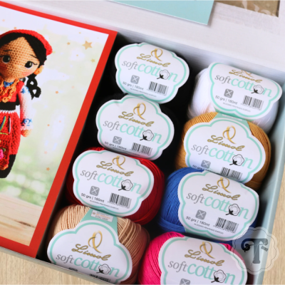 Vários rolos de fio de algodão Soft Cotton da Lionel em diferentes cores numa caixa aberta