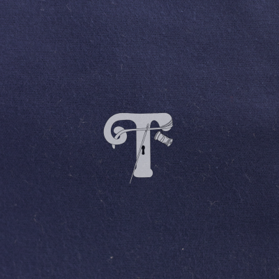 Logótipo branco em tecido azul escuro com agulha e carretel