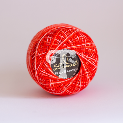 Rolo de linha vermelho e branco com etiqueta preta e dourada