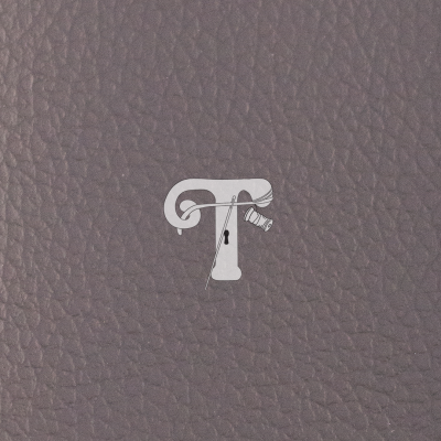 Superfície cinza de couro com letra T branca e agulha com linha desenhadas