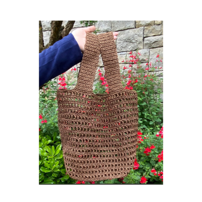 Bolsa de crochet castanha segurada por mão com manga azul