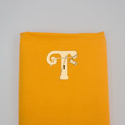 Tecido amarelo com logótipo da letra T e ferramentas de costura