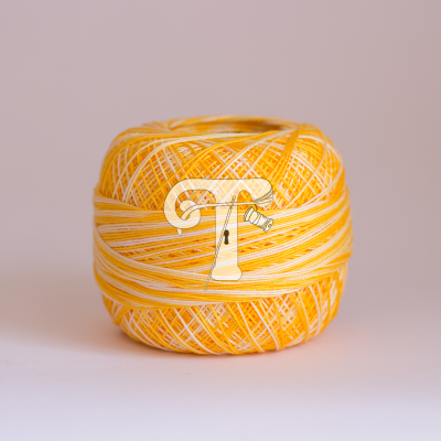 Novelo de linha amarelo e branco sobre fundo rosa e superfície branca