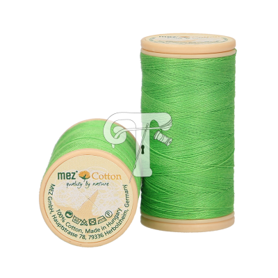 Dois carretéis de linha de costura verde com bases bege e etiqueta visível em um deles