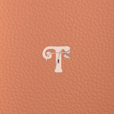 Textura de pele cor de laranja com logótipo branco contendo uma letra T, agulha e carretel