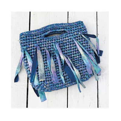 Mala azul de crochet com franjas azuis sobre fundo branco