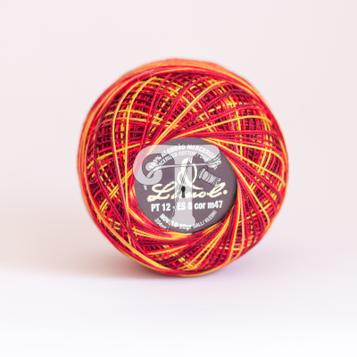 Rolo de linha colorido com etiqueta preta em fundo rosa claro